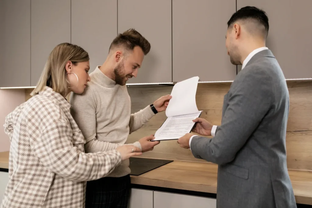 Pareja revisando documentos con un agente antes de firmar la compra de su vivienda